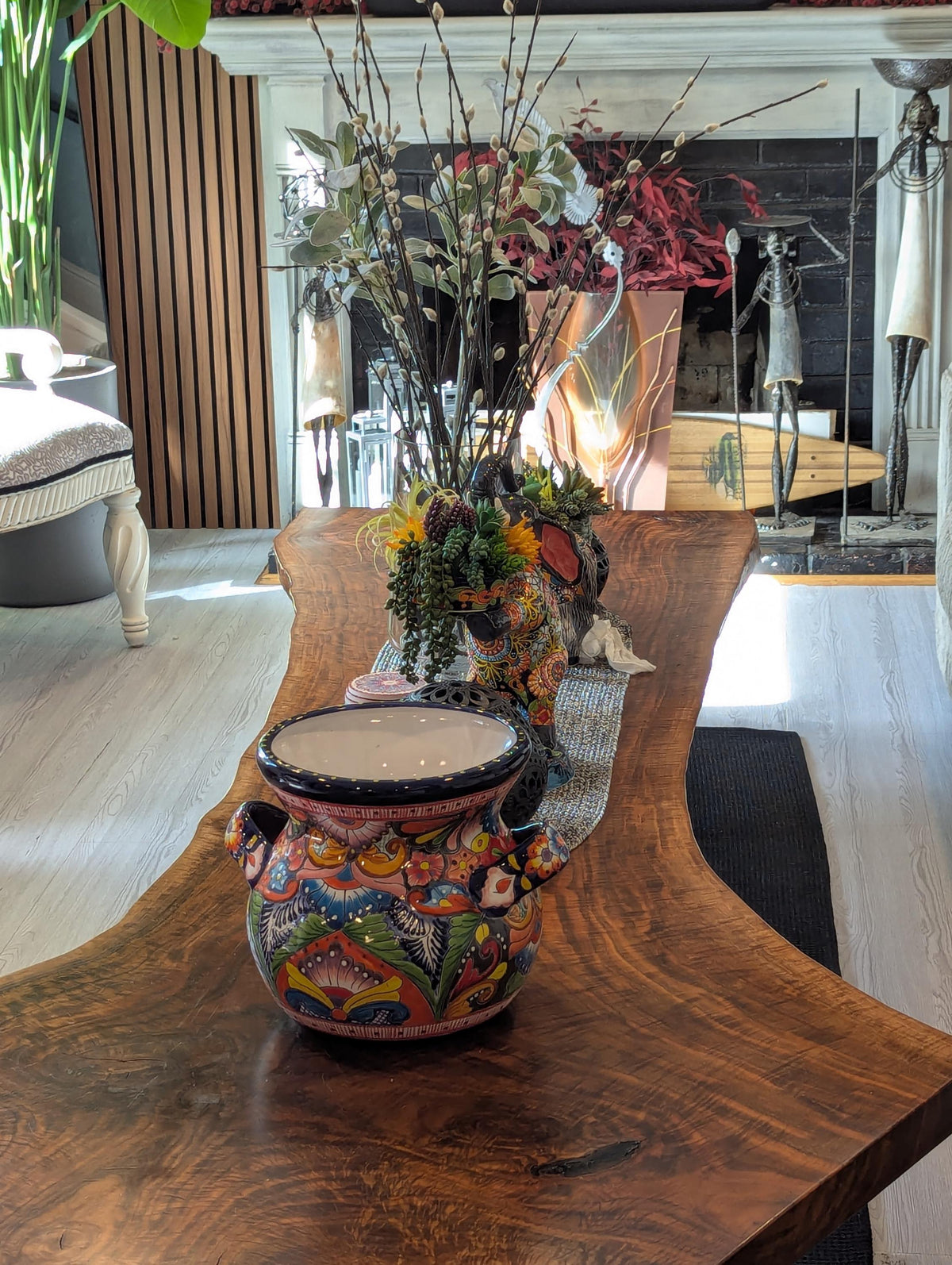 A colorful Talavera ceramic round flower pot with blue trim and handles, displayed indoors.