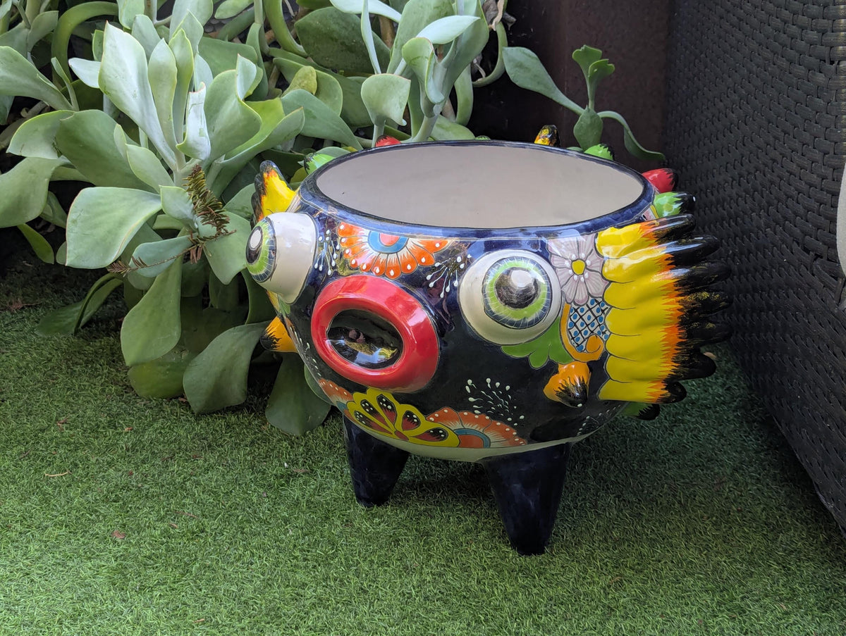 Colorful decorative pot with intricate designs on a green surface.
