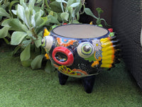 Colorful decorative pot with intricate designs on a green surface.