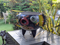Colorful ceramic owl planter on a table in a garden with a dog in the foreground.