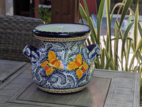 A round, ceramic Talavera planter with blue trim and handles, featuring a floral pattern with yellow and dark blue colors.