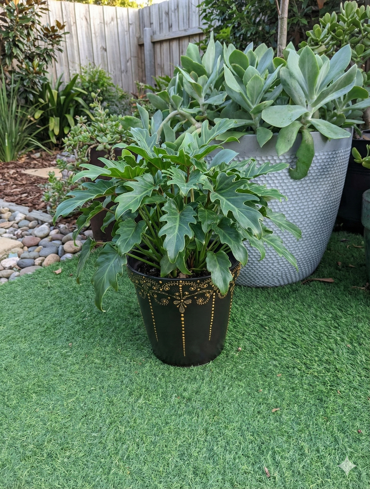 Potted plants on a green artificial grass surface with a garden background