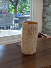 Ceramic vase with embossed design on a wooden table