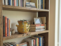 Wooden bookshelf with books, a decorative vase, and a small figurine.