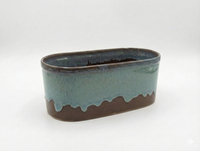 Oval ceramic planter with two-tone glaze on a white background