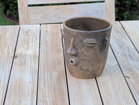 Ceramic face-shaped planter on a wooden table outdoors