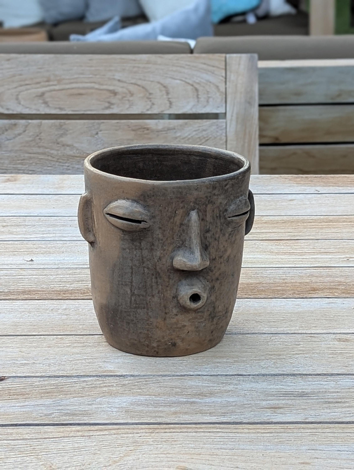 Ceramic face-shaped planter on a wooden surface