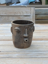Ceramic face-shaped planter on a wooden surface