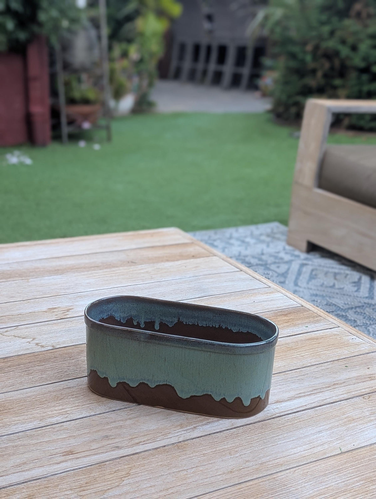 Green ceramic planter on a wooden table outdoors