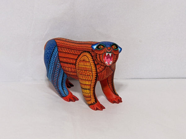 A colorful wooden bear figurine with intricate patterns and vibrant colors, resembling a traditional Oaxacan alebrije.